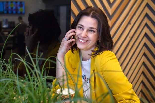 Encantadora mulher falando no celular enquanto relaxa no café