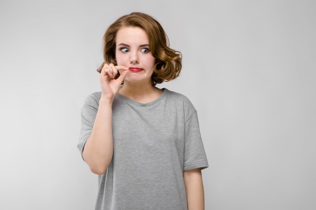 Encantadora mulher jovem em uma camiseta cinza. Uma mulher segura os dedos com os dedos