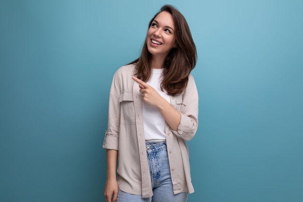 Encantadora mulher morena de camisa e jeans sorrindo sobre fundo azul