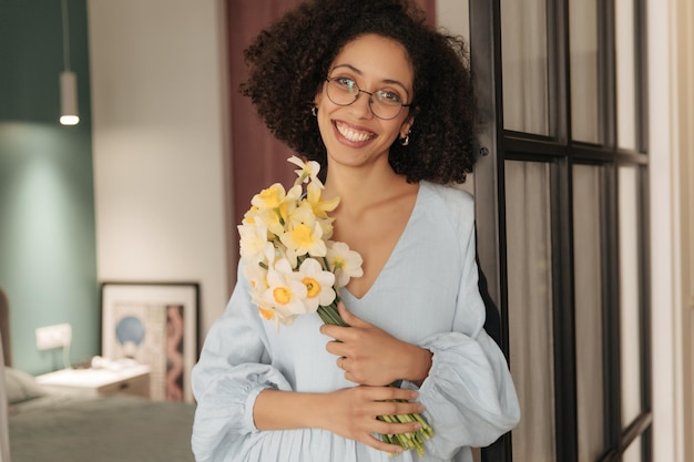 Encantadora mulher negra olhando para a câmera com flores