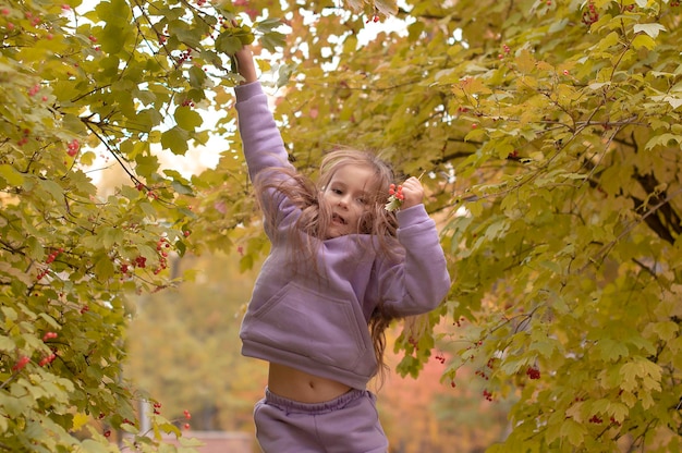 Encantadora niña feliz arroja hojas caídas mientras juega en un parque de otoño y se ríe en un día soleado Sintiendo paz interior felicidad armonía Enfoque selectivo