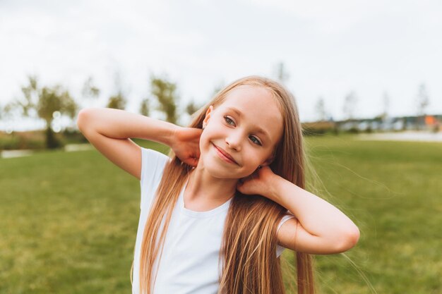 Encantadora niña feliz con cabello rubio al aire libre en el parque Retrato de un niño caucásico disfrutando del sol