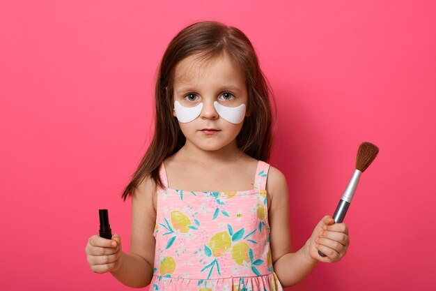 Foto encantadora niña seria con pincel y pomada en manos