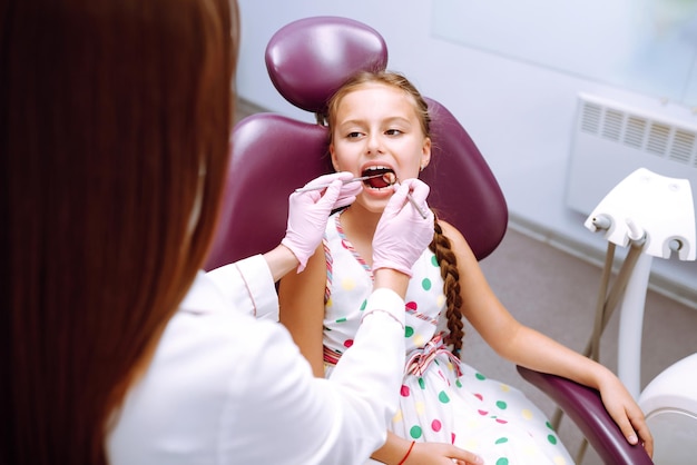 Encantadora niña sonriendo después de hacer un examen en una estomatología pediátrica Cuidado de los dientes de leche