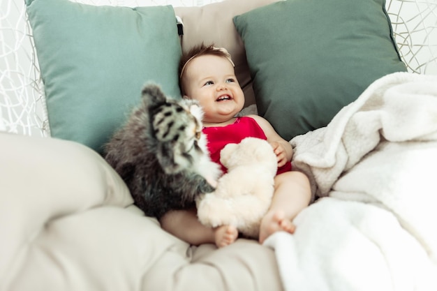 Encantadora niña sonriente yace en la cama con juguetes de peluche Infancia