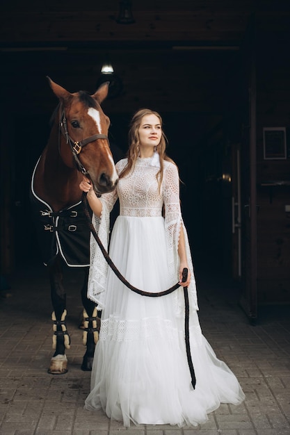 Encantadora novia en estilo boho en un rancho con un caballo