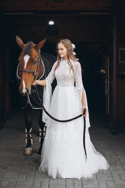 Encantadora novia en estilo boho en un rancho con un caballo