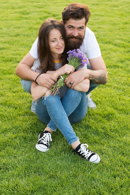 Encantadora pareja abrazándose relajante en prado verde, celebrar el concepto de aniversario.