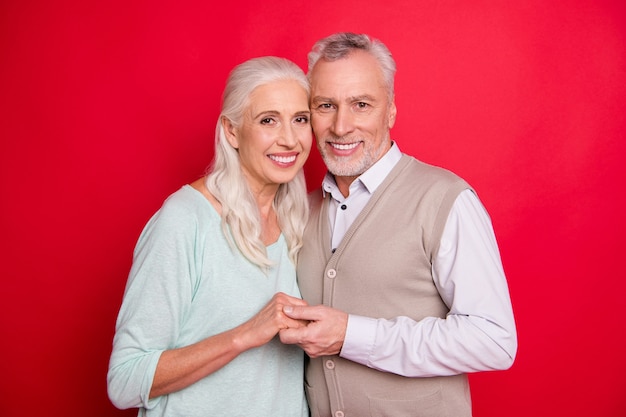 Foto encantadora pareja de ancianos posando contra la pared roja