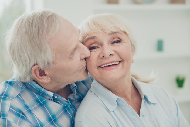 Encantadora pareja de ancianos posando juntos en el interior