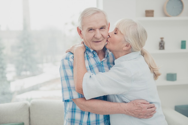 Encantadora pareja de ancianos posando juntos en el interior