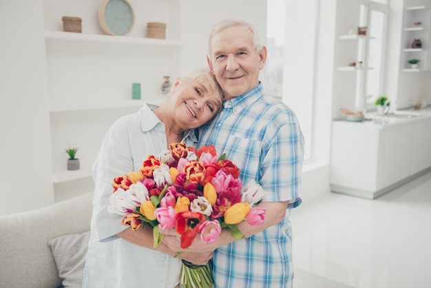 Encantadora pareja de ancianos posando juntos en el interior