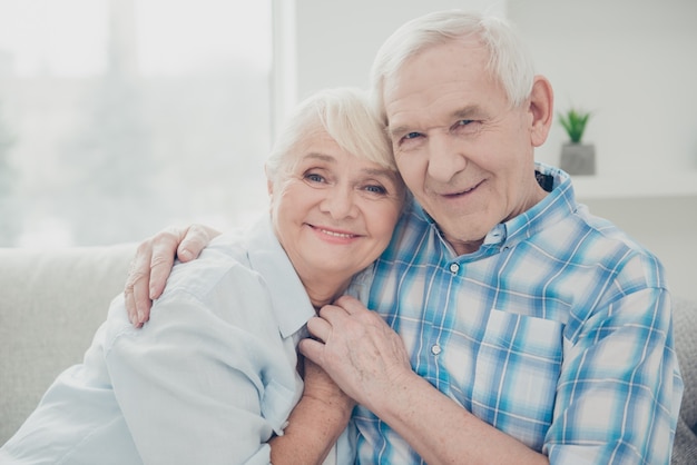 Encantadora pareja de ancianos posando juntos en el sofá