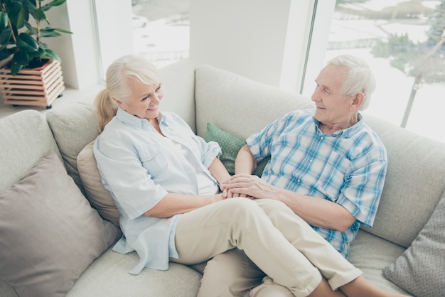 Encantadora pareja de ancianos posando juntos en el sofá