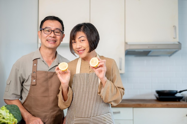 Una encantadora pareja asiática está en la cocina con un delantal preparándose para cocinar su cena juntos