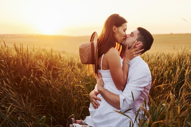 Encantadora pareja besándose y pasando tiempo libre en el campo en un día soleado de verano