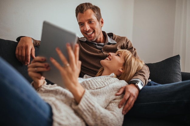 Encantadora pareja disfrutando en casa y usando tableta digital