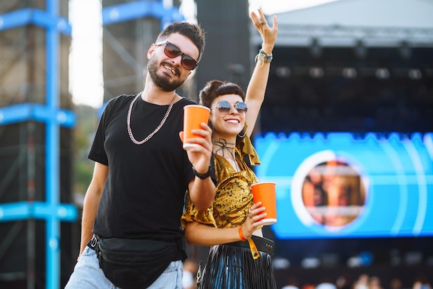 Encantadora pareja divirtiéndose en el festival Jóvenes amigos con cerveza en la fiesta en la playa Vacaciones de verano