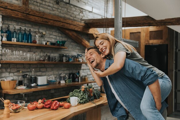 Encantadora pareja divirtiéndose juntos en la cocina rústica