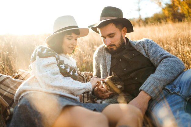 Encantadora pareja hipster con gato Pareja con hermosos sombreros y suéteres Estilo de vida