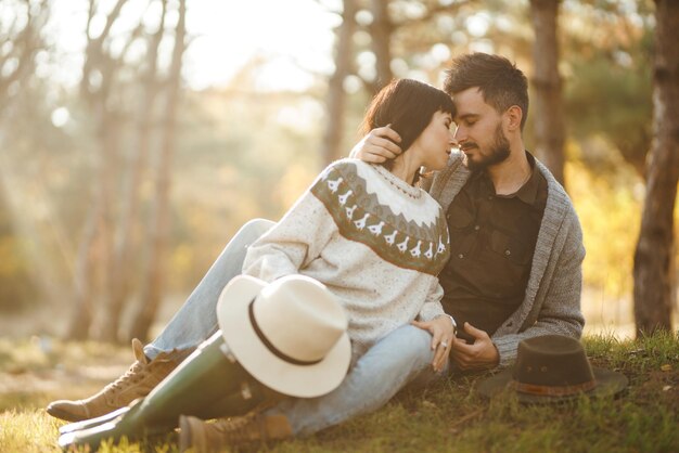 Una encantadora pareja de hipsters mirándose la una a la otra una pareja con hermosos sombreros y suéteres