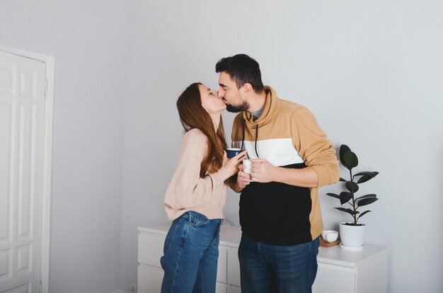 Encantadora pareja joven alegre hombre y mujer besándose en casa