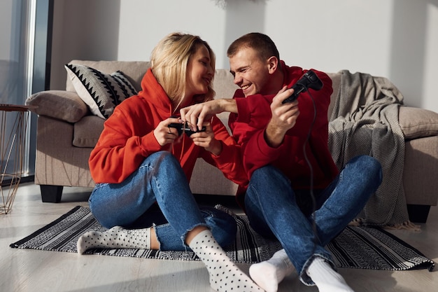 Encantadora pareja joven juntos en casa jugando videojuegos en fin de semana y vacaciones juntos