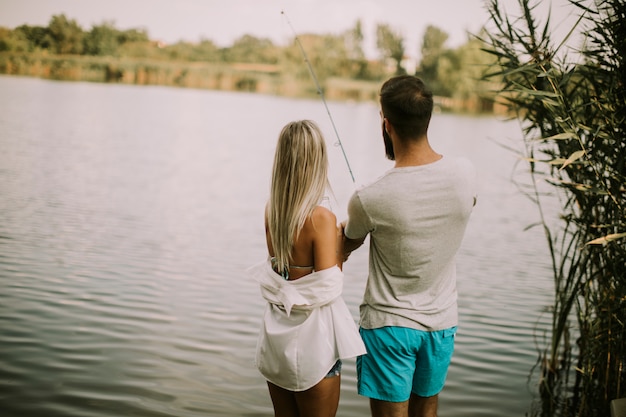 Encantadora pareja joven pescando junto a un lago