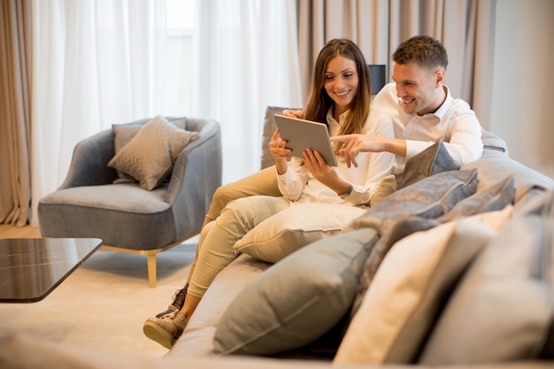 Encantadora pareja joven con tableta digital en la habitación