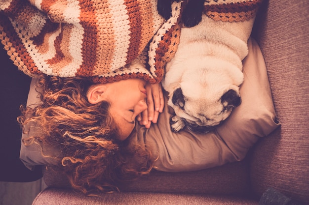 Encantadora pareja mujer perro pug dormir juntos en casa en una tierna y dulce escena romántica. estando más cerca con amor y amistad. verdadera relación entre personas y animales