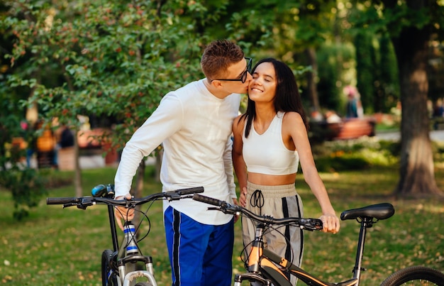 Encantadora pareja de pie con sus bicicletas en el parque