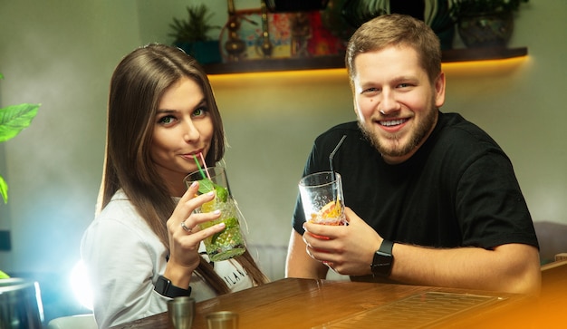 Encantadora pareja relajándose en el bar con cócteles