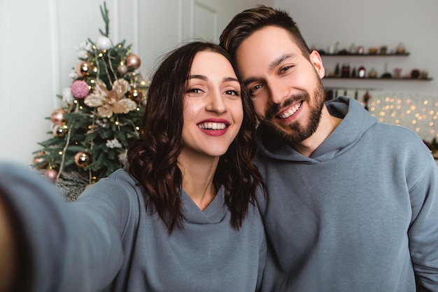 Encantadora pareja romántica joven haciendo selfie tomar guirnaldas de fotos hogar acogedor ambiente interior