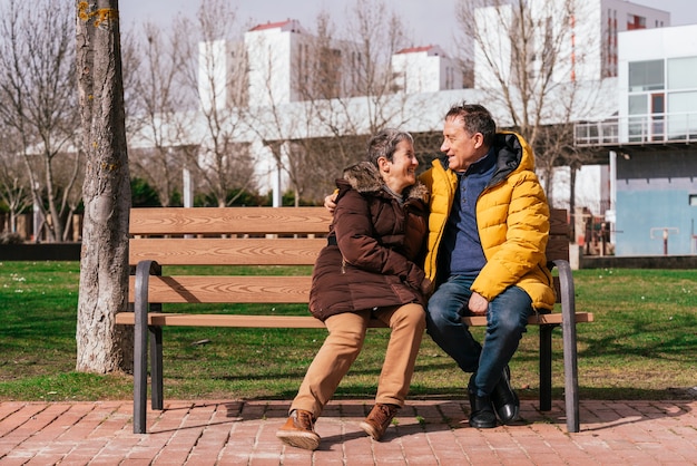 Una encantadora pareja senior relajándose en un banco en el parque en un día soleado