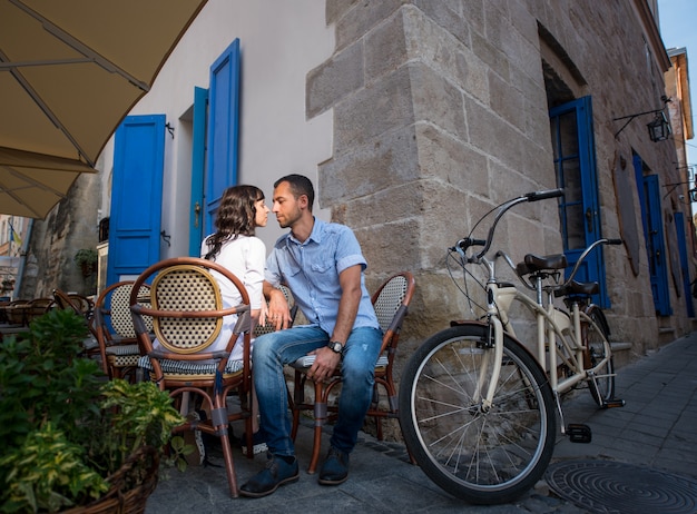 Encantadora pareja sentada en la cafetería de la acera cerca de su bicicleta tándem
