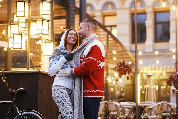 Encantadora pareja se siente feliz en el mercado navideño, rodeada de luces cálidas.