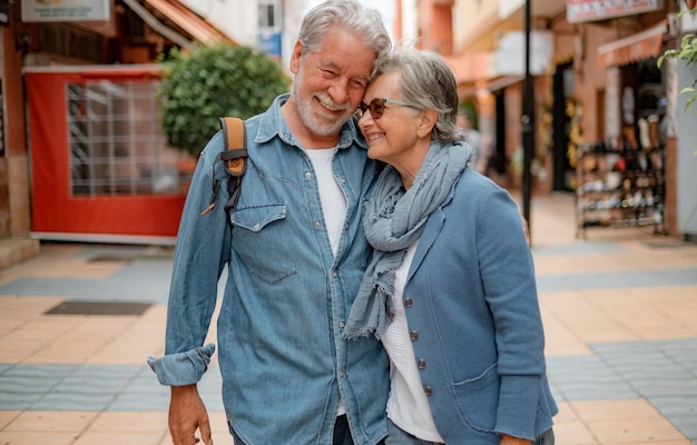 Una encantadora pareja de turistas de edad avanzada sonrientes caminando por la ciudad disfrutando de su tiempo libre o de su jubilación