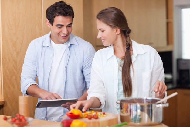 Encantadora pareja usando una tableta para cocinar