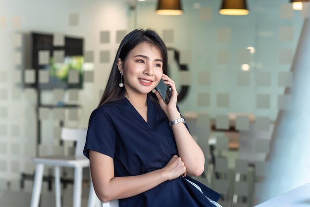 Foto encantadora vista frontal de una mujer asiática hablando por teléfono en un café