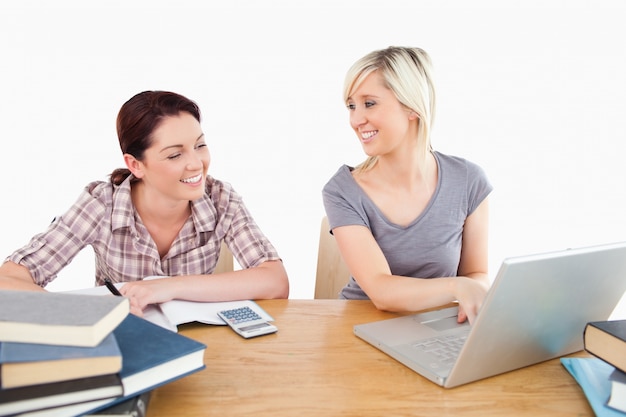 Encantadoras mujeres aprendiendo con laptop y libros