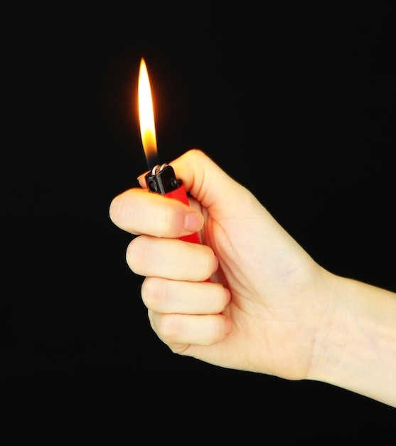 Encendedor en la mano de una mujer aislado en negro