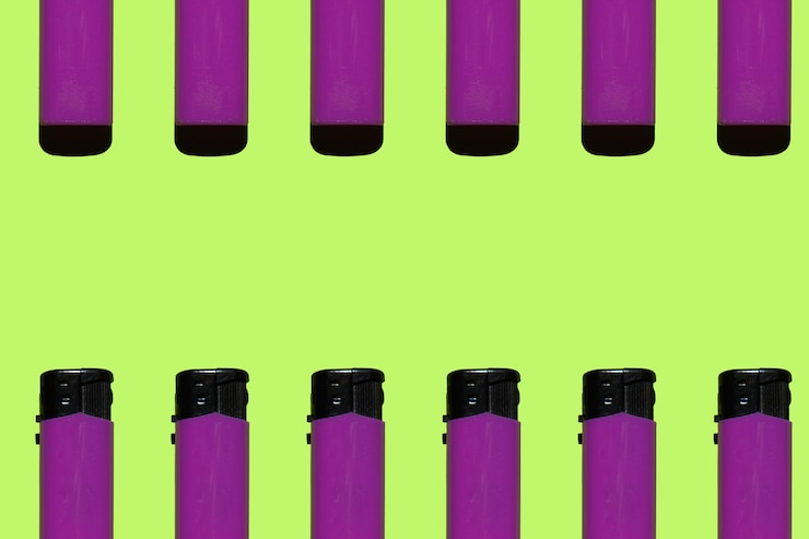 Foto encendedores de cigarrillos de color púrpura sobre un fondo verde concepto de fumar