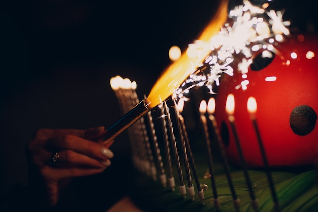 Encender velas con bengalas en una fiesta brillante en la oscuridad.