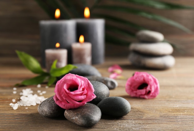 Encender velas de cera gris con rosas y guijarros sobre fondo de madera relajarse concepto
