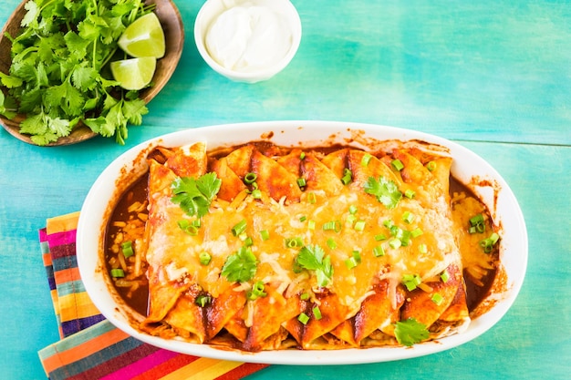 Enchiladas de pollo caseras adornadas con cebollas verdes y cilantro en una cazuela blanca.