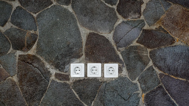 Enchufes eléctricos con paredes con textura de piedra