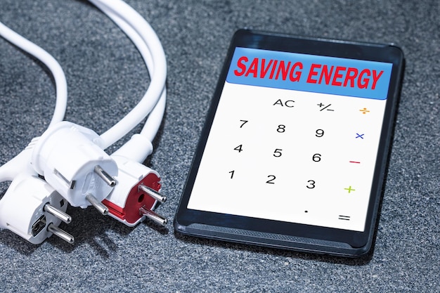 Enchufes eléctricos con tableta digital con texto de AHORRO DE ENERGÍA Concepto de ahorro de energía de eficiencia energética