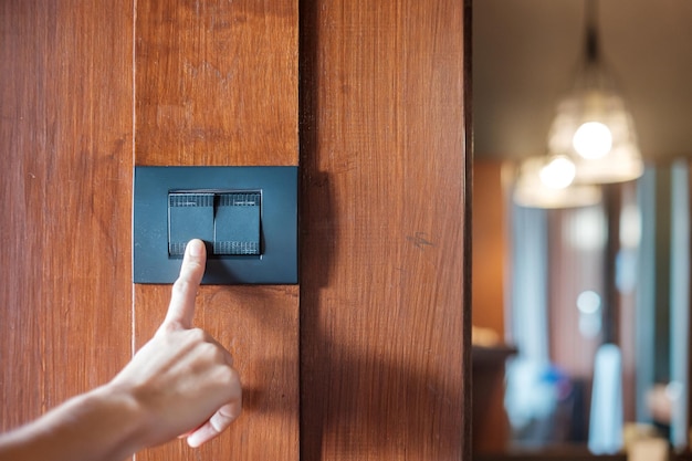 Encienda o apague con el dedo el interruptor de la luz en la pared en el hogar Ahorro de energía eléctrica y conceptos de estilo de vida