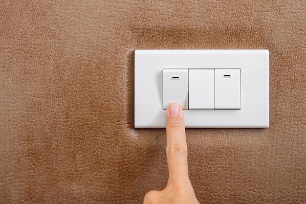 Encienda o apague con el dedo el interruptor de la luz en la pared en el hogar Ahorro de energía eléctrica y conceptos de estilo de vida