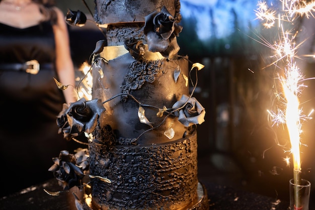 Por encima de las velas encendidas, los fuegos artificiales se colocan en un pastel y una mano se cierne sobre él